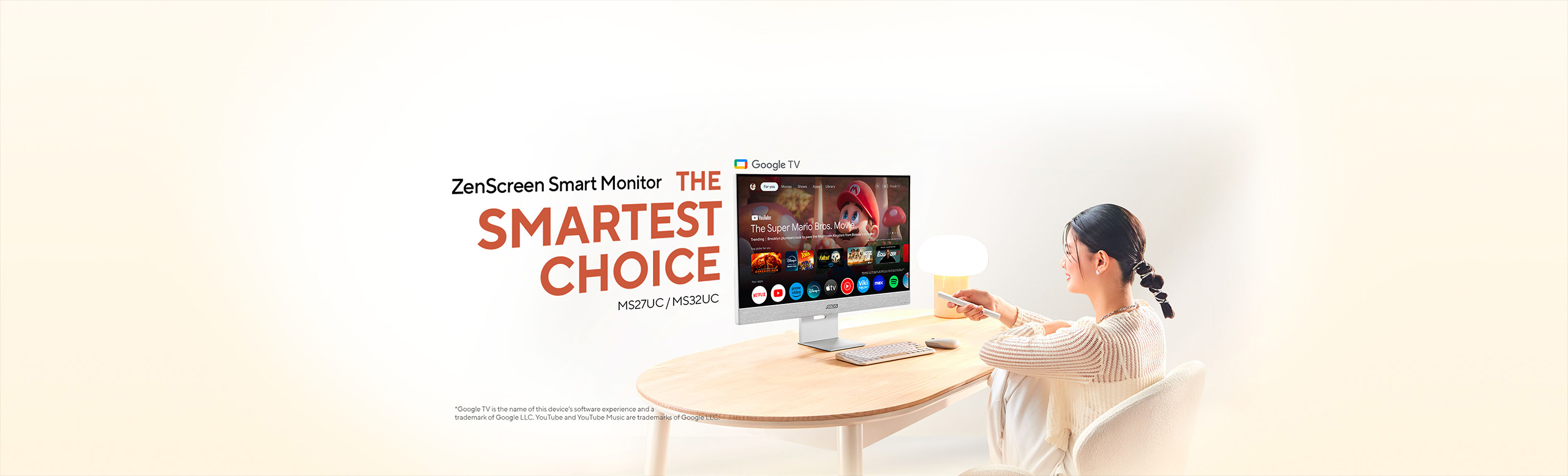 Lifestyle scene showing a woman at a light‑wood table using a remote to control an ASUS ZenScreen Smart Monitor (MS27UC / MS32UC) displaying the Google TV interface under the headline “ZenScreen Smart Monitor – THE SMARTEST CHOICE” on a soft beige background