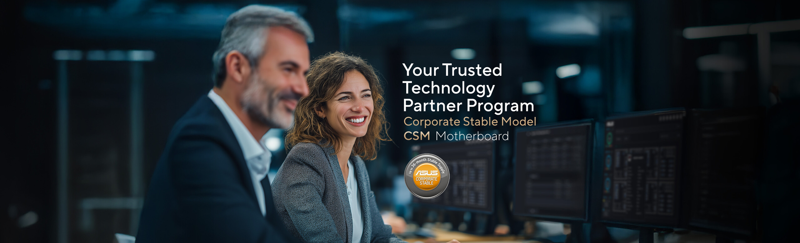 A man in a suit and a woman with wavy, light brown hair wearing a business jacket and white shirt are seated together at a desk in a modern office setting. Computer monitors are visible in the background, alongside promotional text for ASUS Corporate Stable Model (CSM) Motherboard: Your Trusted Technology Partner Program, and a circular badge stating 'Up to 36-month Stable Supply.'