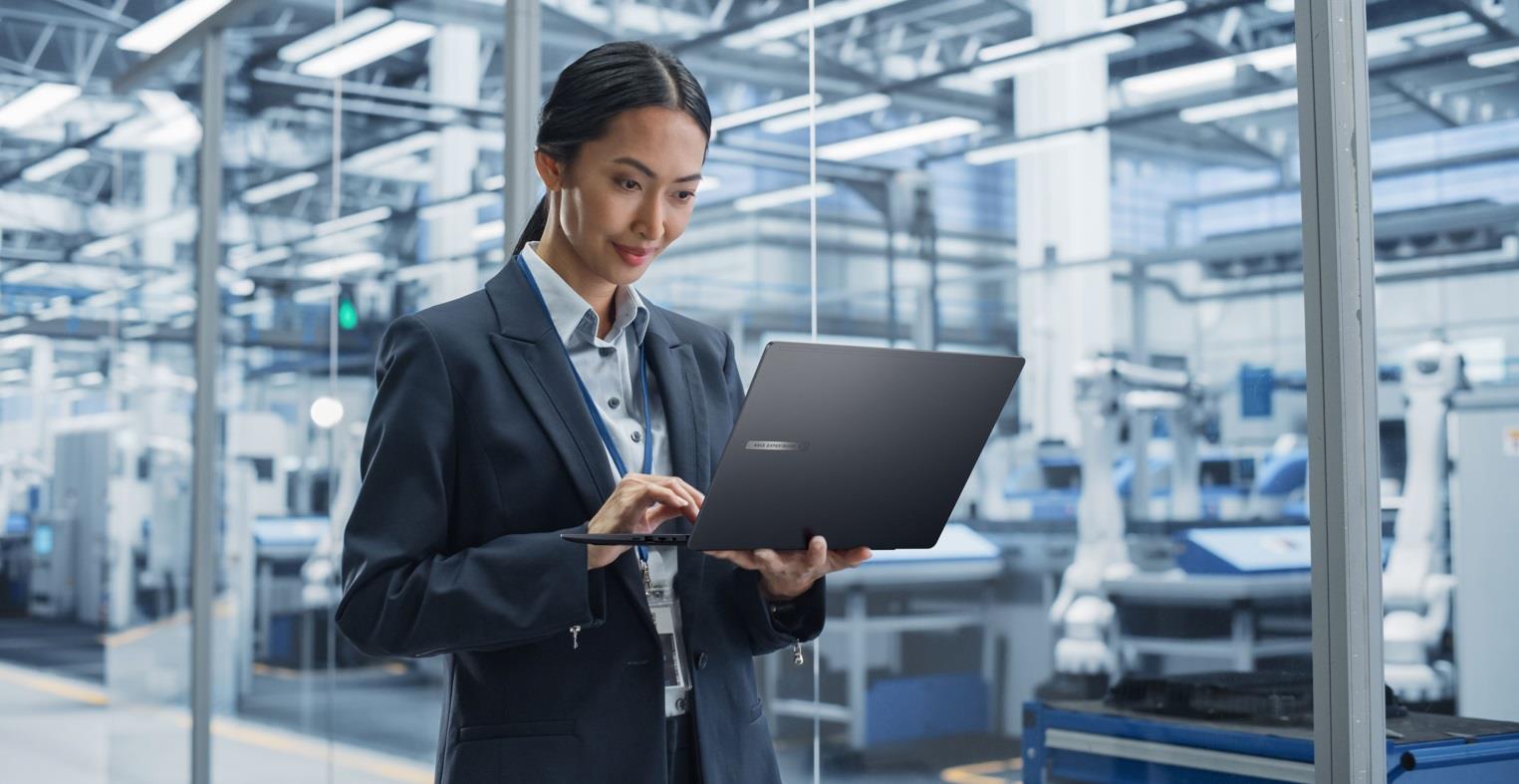 A woman standing in an office environment, using an ASUS laptop