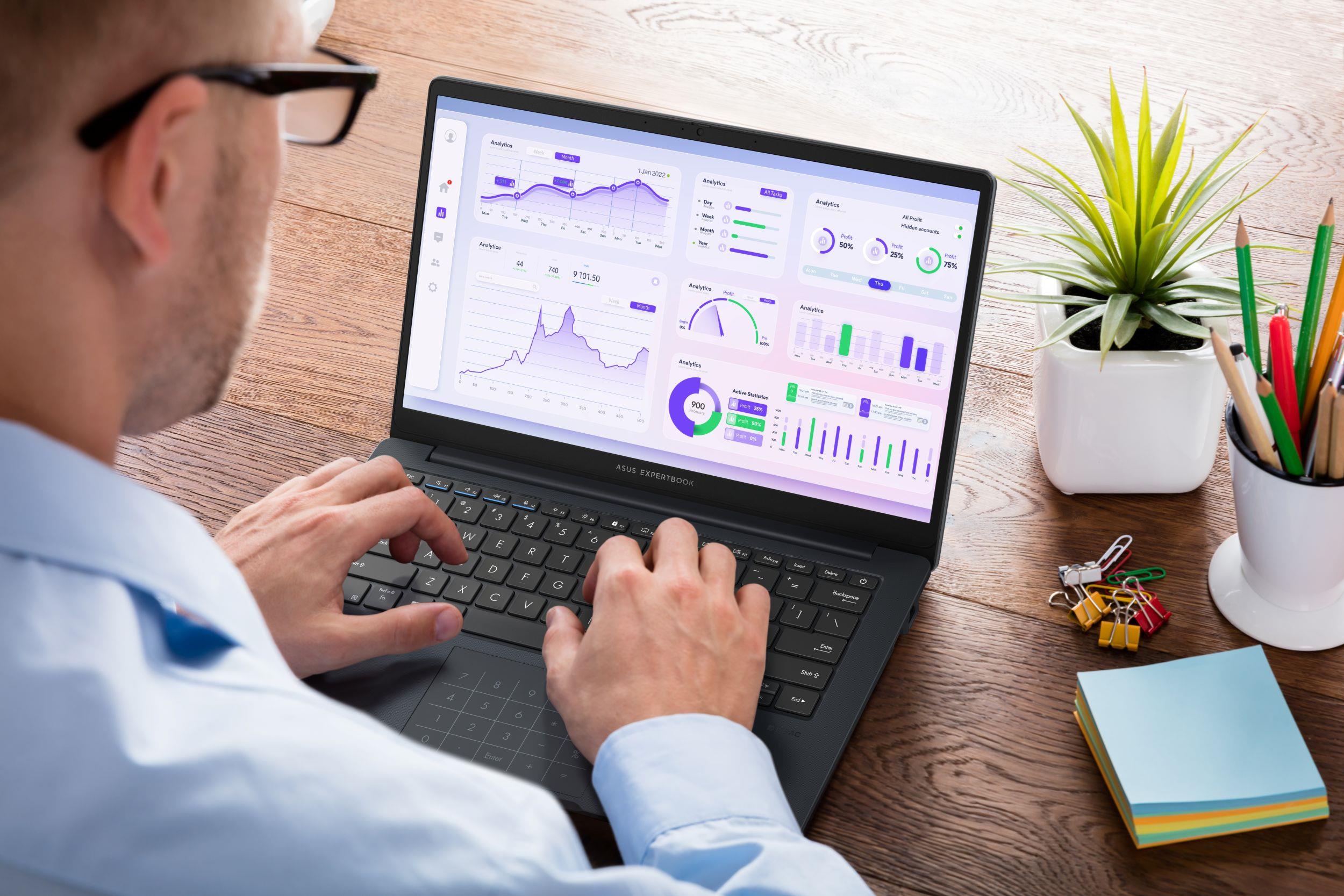 A view over the shoulder of a man using an ASUS laptop for analytics