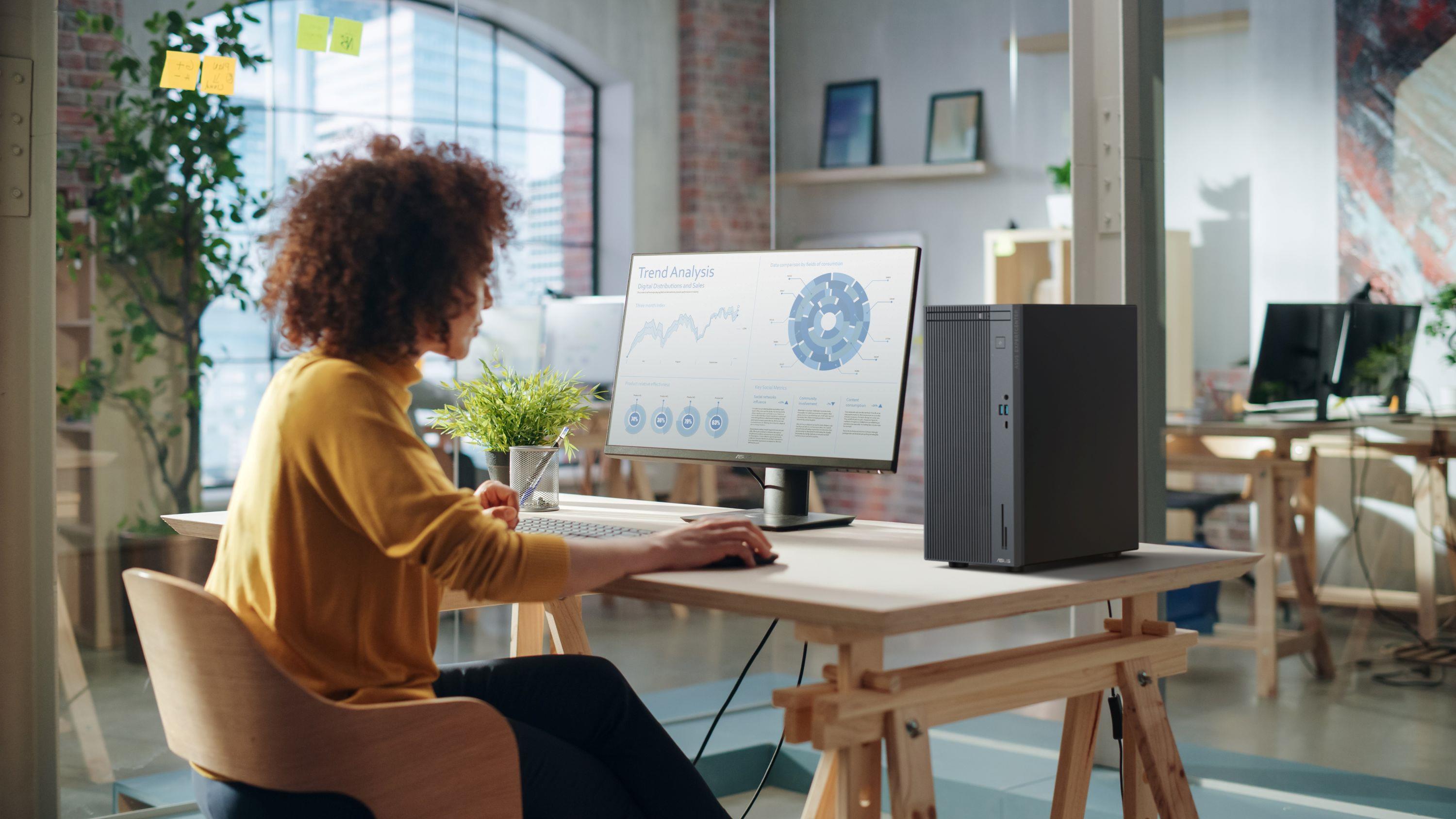 A woman in an open office environment using an ASUS desktop setup
